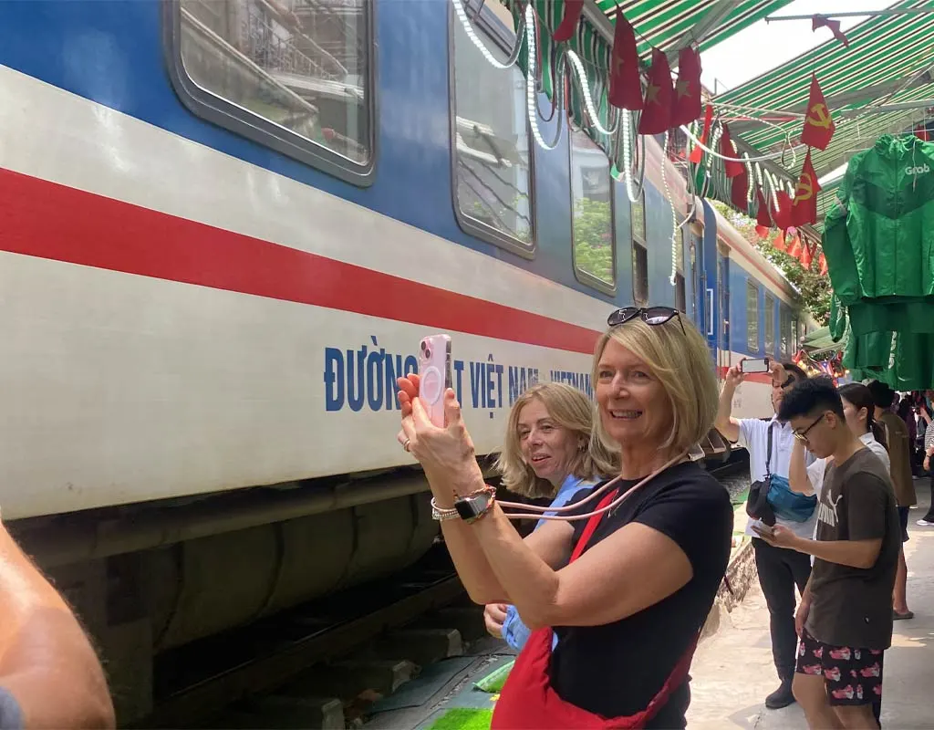 Train passing through Hanoi Train Street beside local cafes